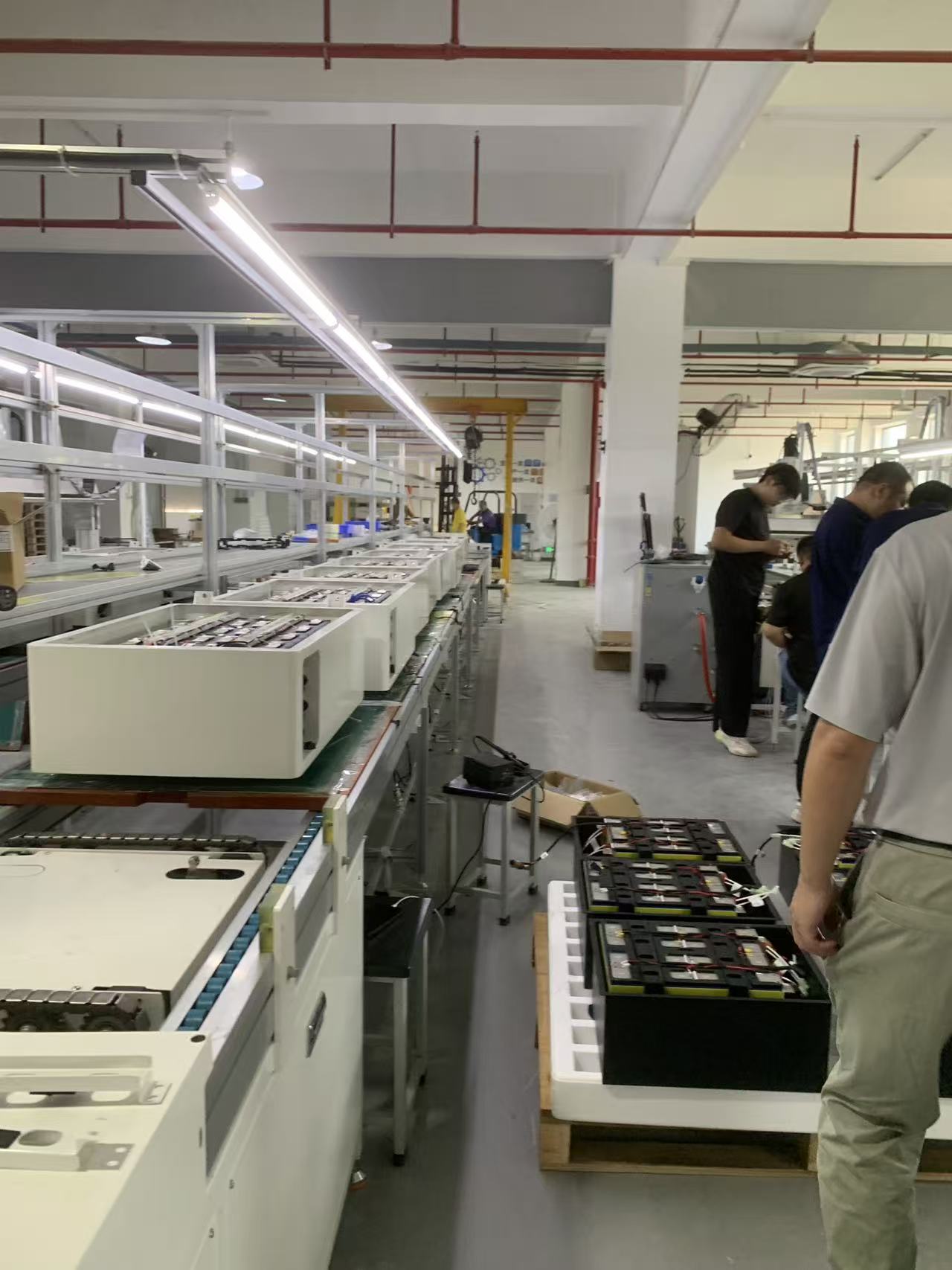Real factory floor — battery pack assembly line with operators at work